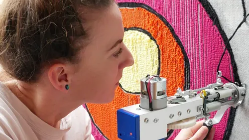 Frau bedient eine Nähmaschine zur Bearbeitung eines farbigen Stoffes.