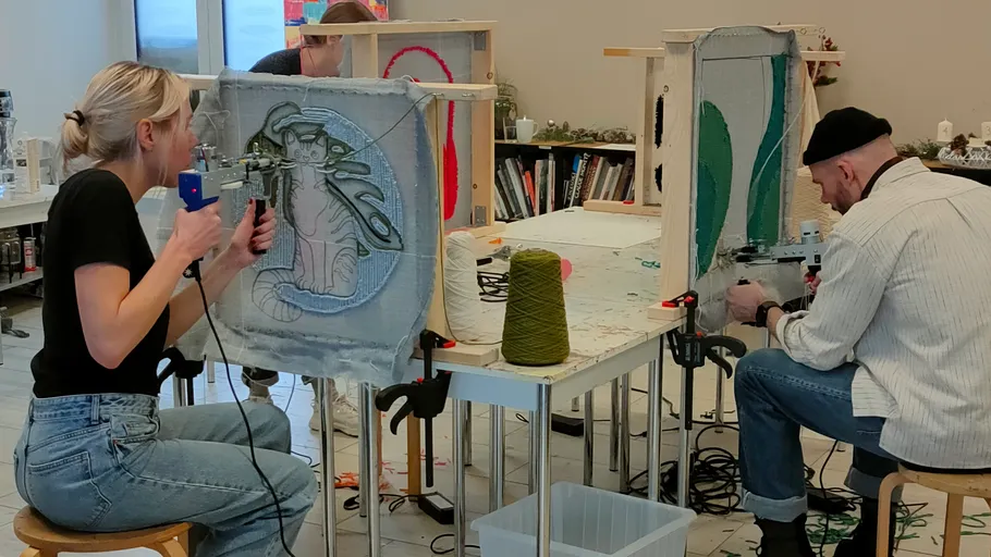 People crafting rugs with tufting guns indoors.