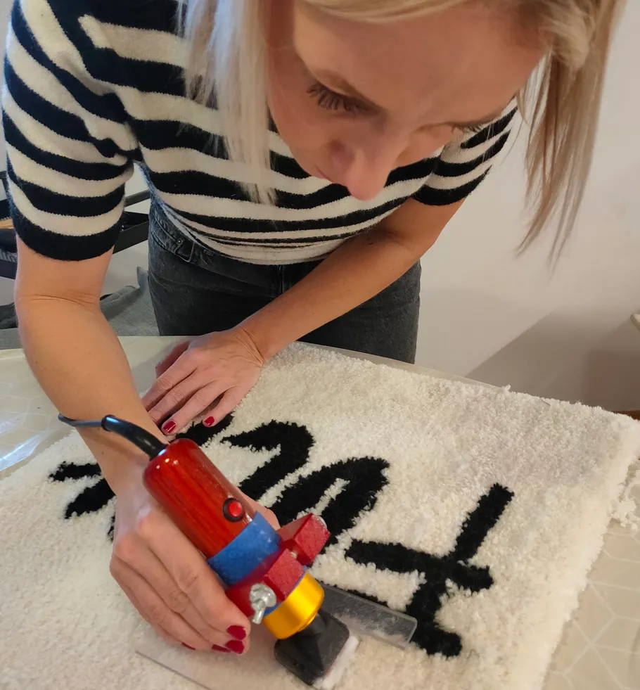 Person using tufting gun on fabric.