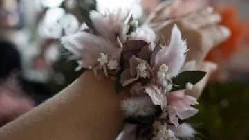 Bracelet made of colorful flowers and feathers on the wrist.