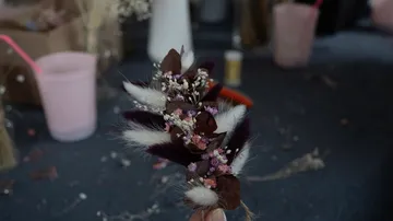 Bouquet of flowers is held surrounded by craft materials.