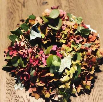 A wreath of colorful, dried flowers on wood.