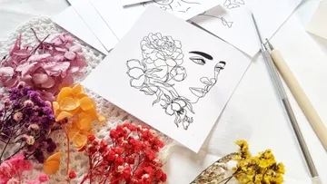 Kunstwerk zeigt Gesichtsskizze umgeben von getrockneten Blumen.