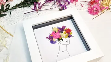 A picture frame with a drawing and dried flowers.