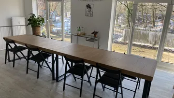 Langer Tisch mit Stühlen, Blick auf einen Wald.