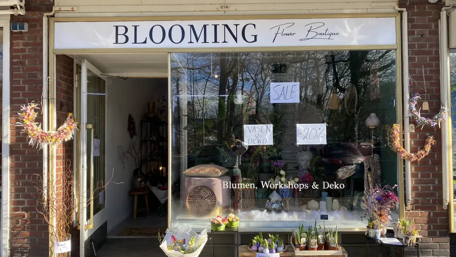 Blumengeschäft zeigt Dekorationen und Sonderangebote in Schaufenster.