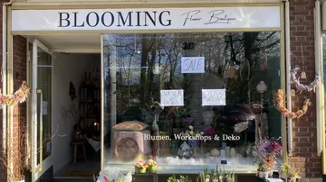 Flower shop shows discount offers in front of a window front.