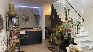 Flower shop with reception desk and stairs in the background.