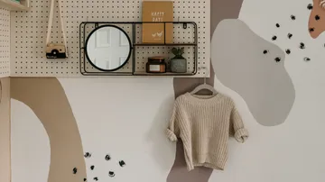 Wall with shelf, mirror, sweater and decorative elements.