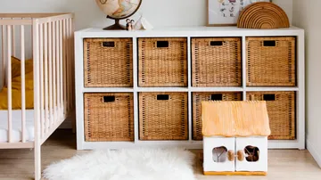 Korbregal mit Spielzeug, Wäschekorb und Gitterbett im Raum.
