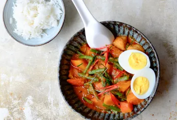 Bowl of vegetables, eggs and rice on table.