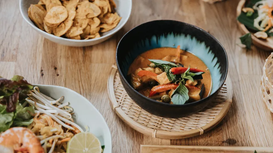 Bowl of curry and vegetables on a wooden table.
