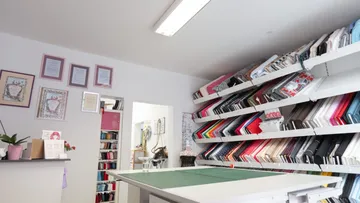 Fabric rack with colorful materials, work surface in the shop.