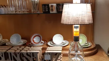 Glass bottle as a lamp, illuminated in a crockery shop.