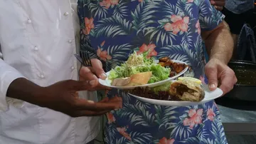 Ein Teller mit Essen wird von zwei Personen gehalten.