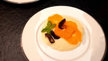 A dessert plate with oranges, herbs and a cream.