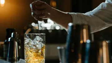 Ein Barkeeper rührt einen Drink in einem Glaskrug.
