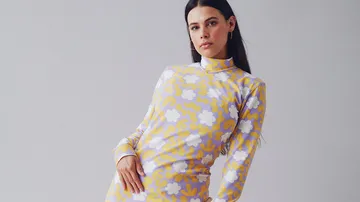 Eine Frau trägt ein gemustertes Kleid und posiert.