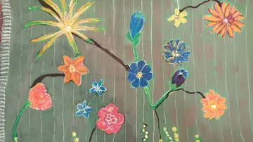 Colourful flowers grow on a green and striped wall.
