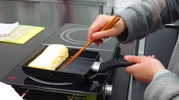 A chef prepares an omelet in a pan.