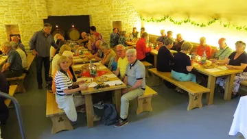 People sit at long wooden tables in a rustic room.