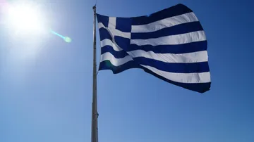 Flag with blue and white stripes waving in sunny sky.