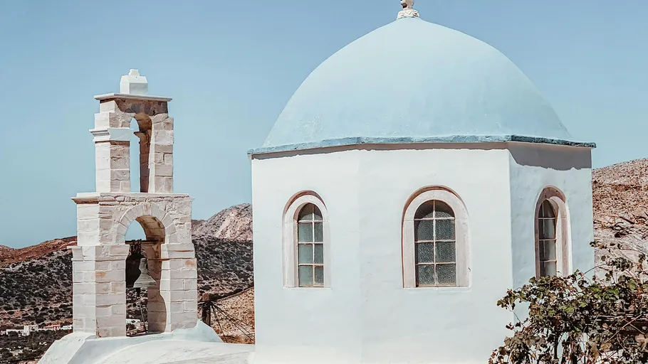 White building with a blue dome surrounded by mountains.
