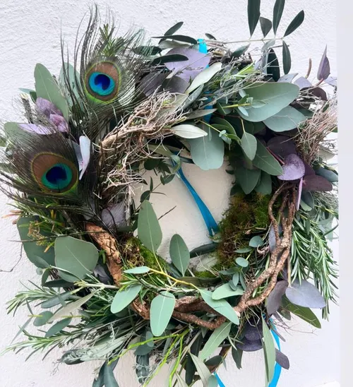 Wreath of green leaves and peacock feathers on the wall