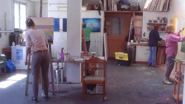 Künstler malen in einem hellen Atelier mit Farben.