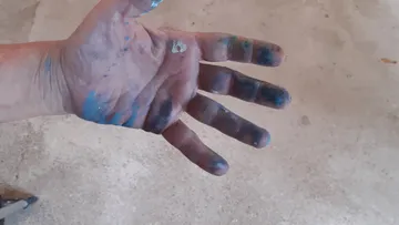 Eine schmutzige Hand mit Farben zeigt kreative Aktivität.