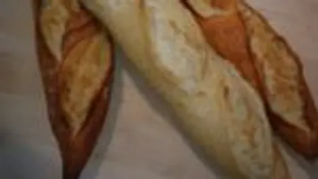 Three loaves of bread lie on a wooden board.