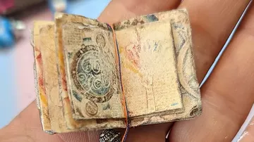 Kleines, gebundenes Buch in Hand, zeigt abgenutzte Seiten.