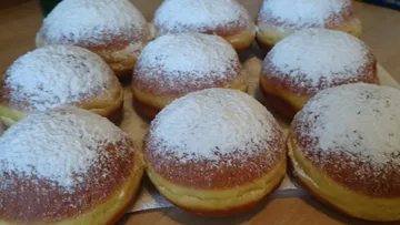 Zwei Reihen von Puderzucker-Brezeln auf einem Tisch.