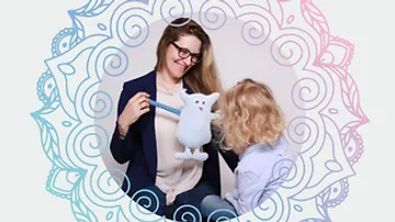 Frau und Kind spielen mit wolligem, blauem Stofftier.