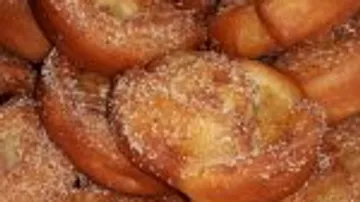 Sugar-sprinkled pastry pieces lie overlapped in a plate.