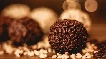 Chocolate ball is lying on wood, surrounded by nuts.