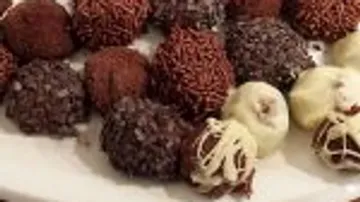 Chocolate truffles lie on a white plate.