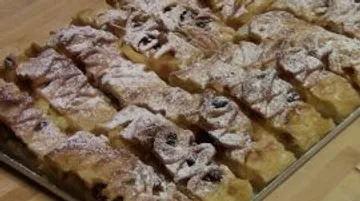 Ein Blechkuchen ist in Stücke geschnitten und bestäubt.