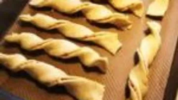 Strips of dough rotate on a baking sheet.