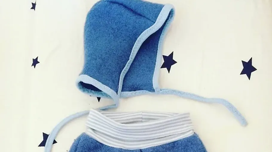 Blaue Babykleidung liegt auf einem weißen Untergrund mit Sternen.