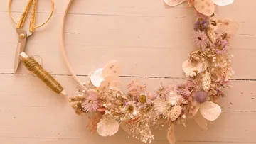 Wreath of flowers rests on table surrounded by tools.