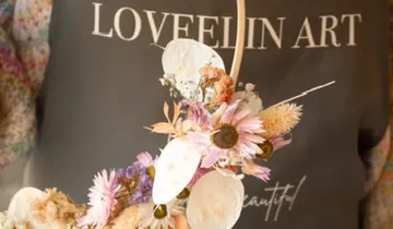 Blumenarrangement in der Hand vor einem Shirt.