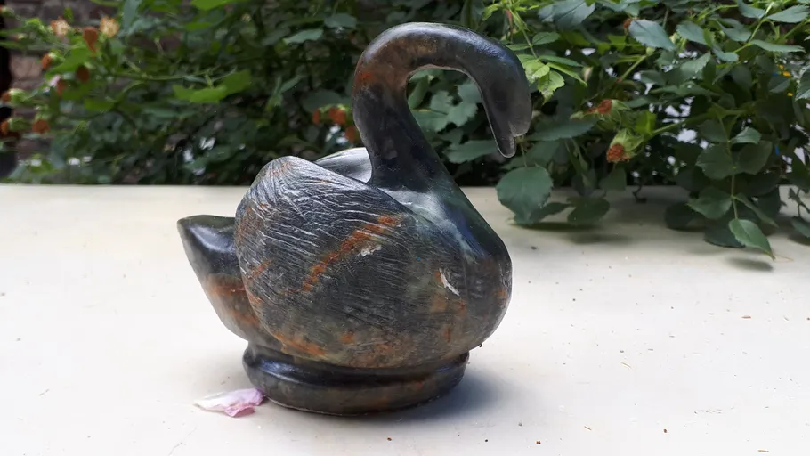 Ein Schwan aus Stein steht auf einem Tisch im Freien.