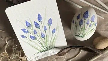 Karte und Ei mit blauen Blumenmotiven auf einem Tisch.