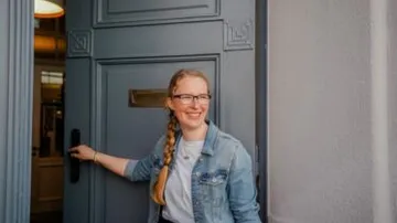 Eine Frau öffnet eine graue Tür im Innenraum.