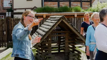 A woman points at something and talks to visitors.