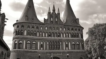 Historisches Gebäude mit spitzen Türmen unter bewölktem Himmel.