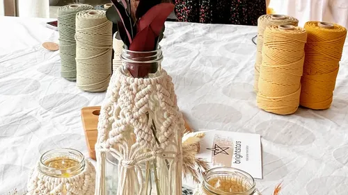 Vase with flowers surrounded by yarn and decoration.