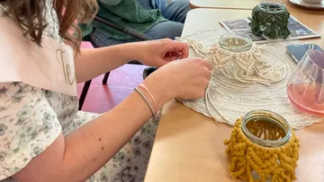 A person knots decorative objects on a table.