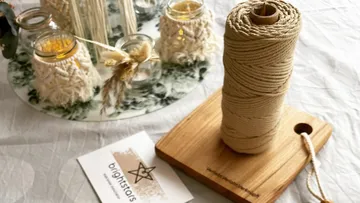String roll stands on a wooden base next to decorative glasses.